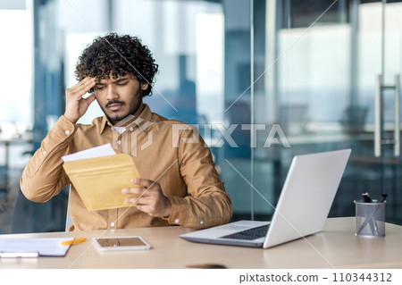 Sad unsatisfied and unhappy business man inside office at workplace, man received mail envelope fox with notification message with bad news, worker reads disappointed. 110344312