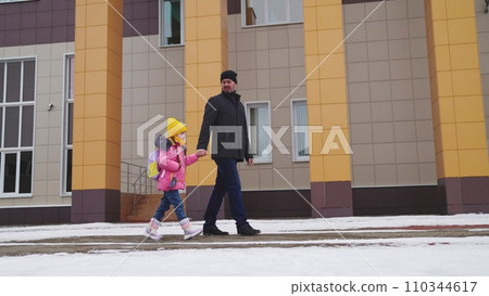 girl holding her father hand, school road education classes, concept happy family, little child kid daughter with school backpack walking through snow boots, school student with backpack, daughter bag 110344617