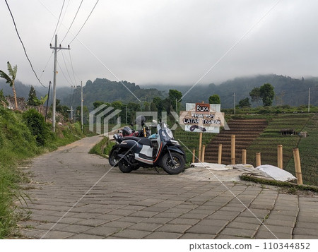 The road is in the middle of forests and mountains which are cloudy and cool 110344852