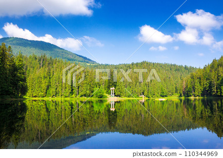 scenery of a synevyr lake in morning light. beautiful summer landscape of carpathian mountains. green environment of national park with coniferous forest beneath a blue sky reflecting in the water 110344969