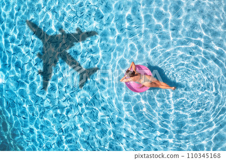 Aerial view of airplane shadow, woman with swim ring, blue sea 110345168