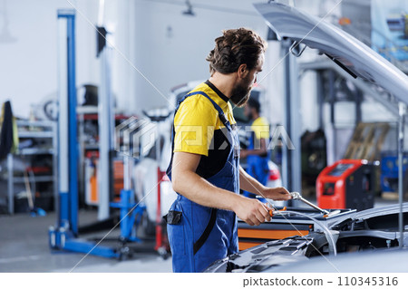 Qualified technician using oil extractor tool to change old transmission fluid with new one in repair shop. Garage workplace employee using professional equipment to do car maintenance Qualified technician using oil extractor tool to change old transmission fluid with new one in repair shop. Garage workplace employee using professional equipment to do car maintenance 110345316