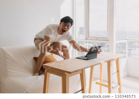 Funny man overly happy and excited with his work success and victory in the computer tablet. 110348573