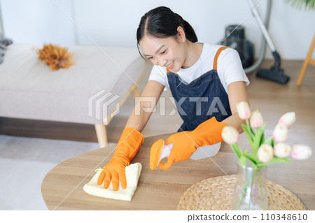 Young Woman happy to house and using rag and diffuser for cleaning table at home 110348610