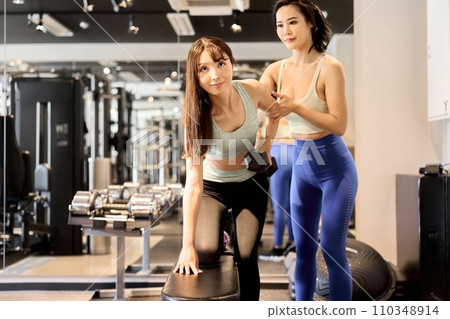 女人用單手啞鈴划船訓練背部和手臂 女人用單手啞鈴划船訓練背部和手臂 110348914