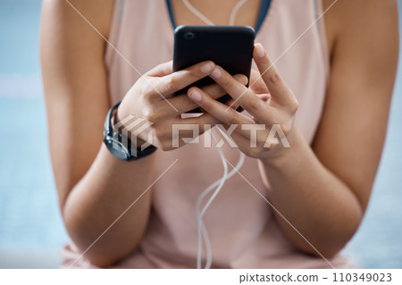 Fitness app, phone and communication while typing on phone in sportswear to track progress on smart device with fast network. Close up hands of a woman listening to music or podcast during training 110349023