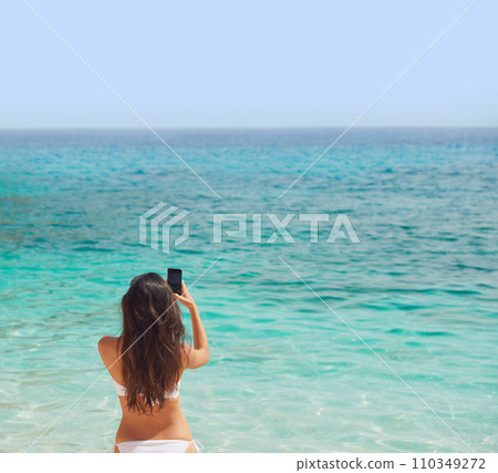 Beautiful woman taking photos with smart phone technology on paradise beach destination summer wanderlust vacation Beautiful woman taking photos with smart phone technology on paradise beach destination summer wanderlust vacation 110349272