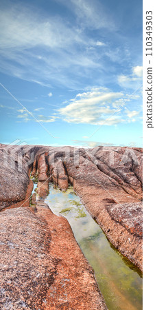 Stream, water or inlet on rocky terrain outside under cloudy blue sky copyspace during summer. Nature, the wilderness and freedom on a sunny day for eco friendly environmentalism and conservation 110349303