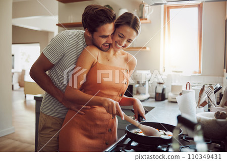 Happy, loving and cooking couple bonding and having fun while spending time together at home. Playful, fun and smilinghusband and wife hugging while preparing a meal and sharing a romantic moment 110349431