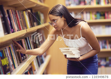 Library, books and woman reading print book for her college or university education and learning. Knowledge of young gen z scholarship student at shelf, studying for an English project exam or test 110349678