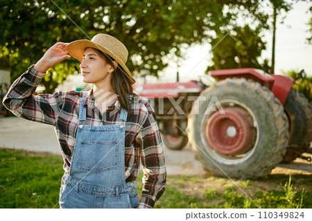 Farm, tractor and a woman in a hat in nature or field farming food, fruits and vegetables. Agriculture and natural environment with farmer in the countryside in the summer sun working on harvest Farm, tractor and a woman in a hat in nature or field farming food, fruits and vegetables. Agriculture and natural environment with farmer in the countryside in the summer sun working on harvest 110349824