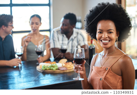 Portrait of a woman at a cheese and wine event with diverse friends at a modern restaurant. Happy girl having fun and holding a luxury glass of an alcohol for a toast at the table of a formal party. 110349931