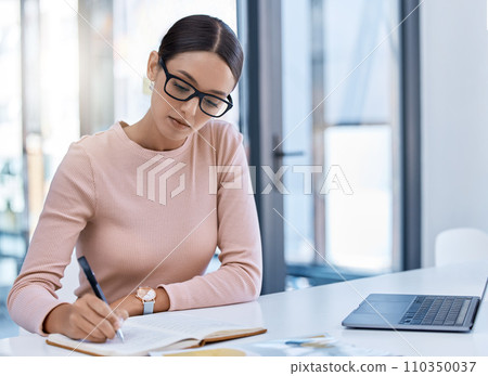 Planning, thinking and strategy with business woman writing notes while working on a laptop in a corporate office. Professional assistant plan schedule and meetings, using journal to write reminder Planning, thinking and strategy with business woman writing notes while working on a laptop in a corporate office. Professional assistant plan schedule and meetings, using journal to write reminder 110350037