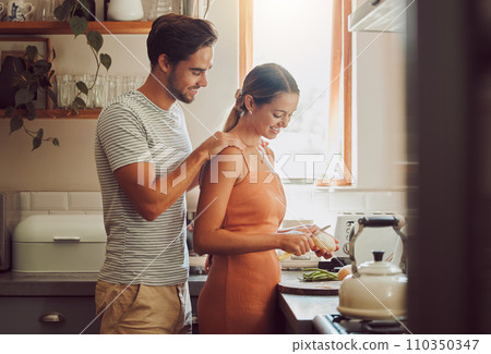 Romantic, caring and loving young couple supporting each other while preparing a meal in the kitchen. Man and woman in a happy, stressless and relaxed relationship together cooking at home. 110350347