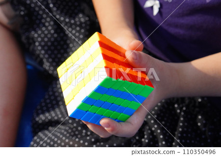 An elementary school girl is playing with a 6x6 Rubik's cube, making patterns. 110350496