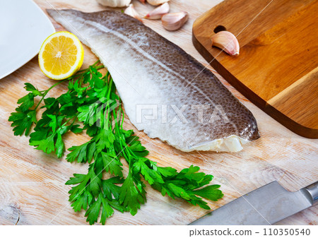 Raw cod fillet with garlic and lemon on wooden surface Raw cod fillet with garlic and lemon on wooden surface 110350540