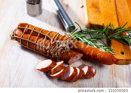 Sliced half-smoked sausages on wooden table Sliced half-smoked sausages on wooden table 110350563