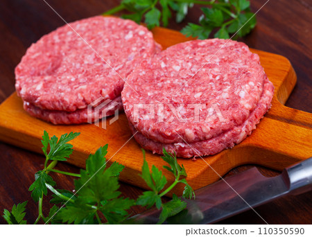 Raw meat burger cutlet with greens on wooden surface 110350590