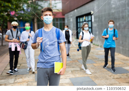 Confident teen boy in medical mask going to lessons on autumn day 110350632