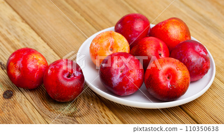 Sweet red plums on wooden table Sweet red plums on wooden table 110350638