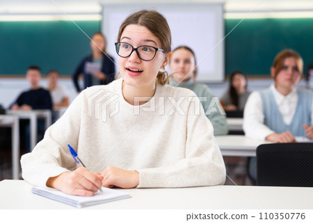 Female student sit at desk and makes notes 110350776