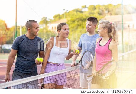 Four smiling sportsmens men and women with rackets emotionally talking and laughing Four smiling sportsmens men and women with rackets emotionally talking and laughing 110350784