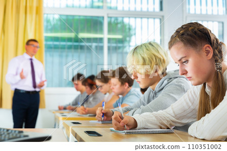 Teenage students studying in classroom with teacher Teenage students studying in classroom with teacher 110351002