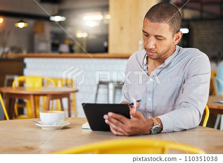 Serious freelance business man working in a coffee shop doing remote work for his startup. Young male entrepreneur using a tablet planning growth strategy in a cafe and writing notes Serious freelance business man working in a coffee shop doing remote work for his startup. Young male entrepreneur using a tablet planning growth strategy in a cafe and writing notes 110351038