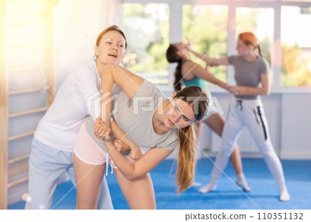 Teenage girl practicing basic skills in mock bout with female self defense instructor Teenage girl practicing basic skills in mock bout with female self defense instructor 110351132