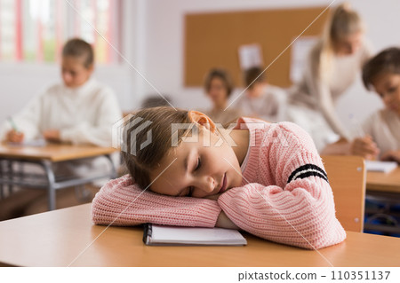 Tired bored teenage schoolgirl sleeping at desk closeup Tired bored teenage schoolgirl sleeping at desk closeup 110351137