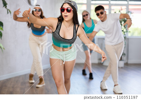 Group of young women and young guy in sunglasses dancing hip hop Group of young women and young guy in sunglasses dancing hip hop 110351197