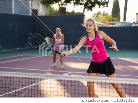 Caucasian woman wearing in pink t-shirt and skirt playing tennis match during training Caucasian woman wearing in pink t-shirt and skirt playing tennis match during training 110351382