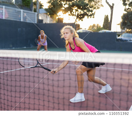 Young woman in skirt playing tennis on court Young woman in skirt playing tennis on court 110351392