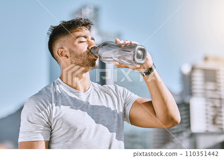 Fitness, healthy thirsty man drinking water while he is exercising outside in sportswear. Runner, cardio workout and active lifestyle for strong athletic body or mental discipline. 110351442