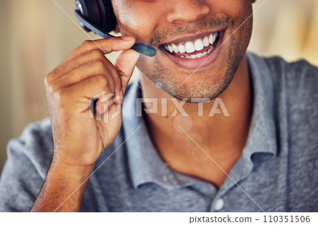 . Happy, smiling and friendly call center agent wearing headset while working in an office. Closeup smile of a confident man consulting and operating helpdesk for customer sales and service support. . Happy, smiling and friendly call center agent wearing headset while working in an office. Closeup smile of a confident man consulting and operating helpdesk for customer sales and service support. 110351506