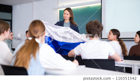 Female teacher tells her classmates about the country of Russian, holding flag in her hands Female teacher tells her classmates about the country of Russian, holding flag in her hands 110351542