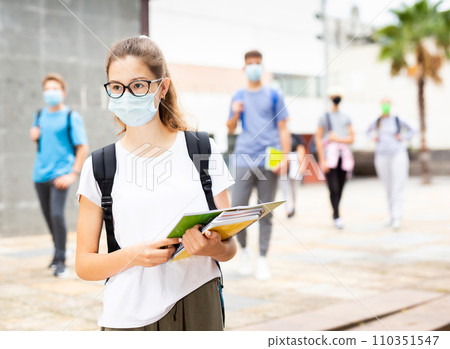 Teenage girl in protective mask going to school lessons 110351547