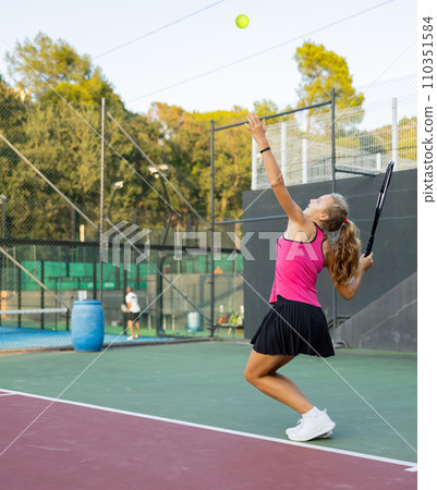 Young woman in skirt playing tennis on court Young woman in skirt playing tennis on court 110351584