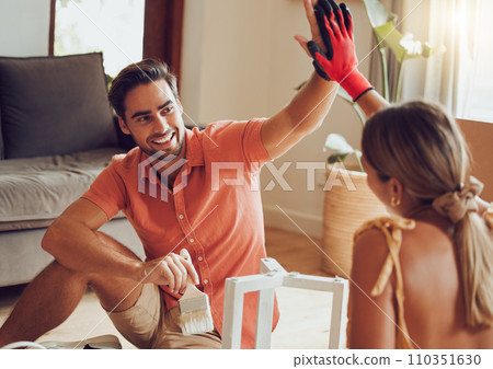 Couple high five for motivation, success and support after a home improvement and maintenance job. Young smiling partners happy and excited painting and sitting on a living room floor doing diy 110351630