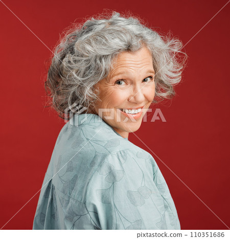 .. Confident, happy and smiling senior woman feeling playful and cheerful while posing against red studio background. Portrait of a beautiful, older and retired lady looking back with grey hair. .. Confident, happy and smiling senior woman feeling playful and cheerful while posing against red studio background. Portrait of a beautiful, older and retired lady looking back with grey hair. 110351686