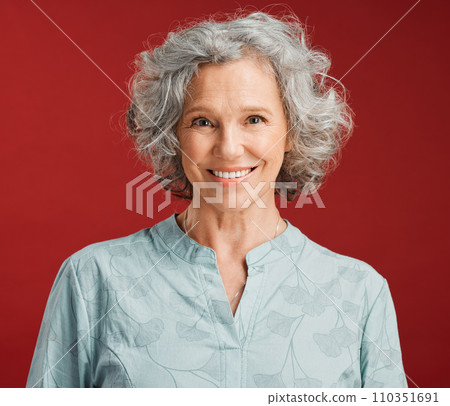 . Portrait of senior, happy and cheerful woman standing against a red studio background. Mature woman with healthy, white and clean teeth showing oral and dental health with a friendly bright smile. . Portrait of senior, happy and cheerful woman standing against a red studio background. Mature woman with healthy, white and clean teeth showing oral and dental health with a friendly bright smile. 110351691