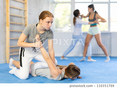 Teenage girl practicing painful armlock in sparring during self defense class 110351789