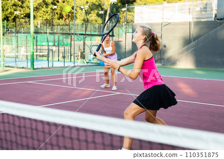 Active young tennis girl dressed in pink t-shirt and skirt on court ready for playing and training 110351875