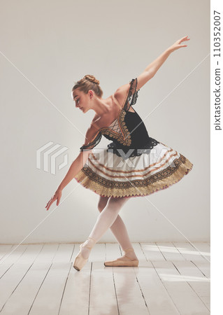 Female ballerina or ballet performer in traditional tutu design dress or costume dancing, practicing or performing. Millennial dancer or artist in full body, elegant bending down pose in a studio 110352007