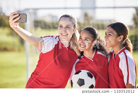 Selfie, soccer and sports team smiling and feeling happy while posing for a social media picture. Diverse and young girls standing together on a football field. Friends and teammates enjoying a match 110352012