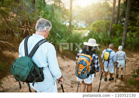 . Hiking, adventure and exploring with a group of senior friends walking on a trail in the forest or woods. Rearview of retired people taking a hike or journey on a discovery vacation outdoors. 110352130