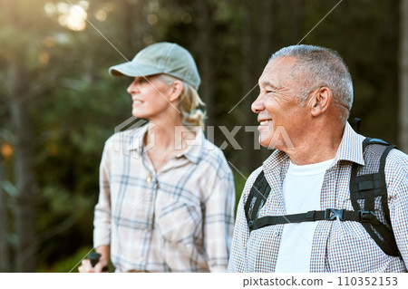 Mature man and woman hiking, smiling and looking at the view in nature. Fit local travel guide showing an active female tourist the natural landscapes while walking a trail outdoors in the wilderness 110352153
