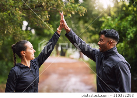Athletic couple high five while exercising in a park or forest, celebrating and winning before a run. Fit boyfriend and girlfriend bonding while keeping fit and healthy. Fun lovers being active 110352298