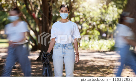 Female wearing covid mask cleaning the park for a clean, hygiene and safe green outdoor environment. Community service, volunteers or activist workers with rubbish, trash and garbage in a plastic bag 110352923