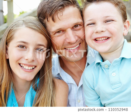 Dad and his little ones. Handsome father embracing his teen daughter and young son while outdoors. 110352948